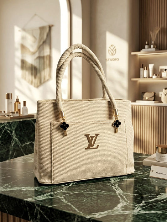 Ivory luxury tote bag with rope handles and gold hardware on marble surface
